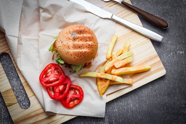 Hamburgers faits maison servis avec des frites et des tomates sur une table en bois. Restauration rapide et malbouffe. - Photo, image