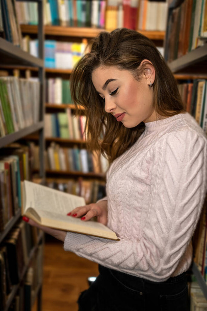 μαθητριούλα ανάγνωση βιβλίου στη βιβλιοθήκη του πανεπιστημίου, έννοια της εκπαίδευσης - Φωτογραφία, εικόνα