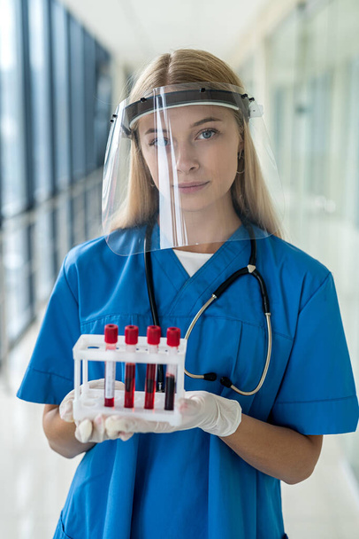 fiatal nővér áll a folyosón, és tart egy tesztet a koronavírus - Fotó, kép