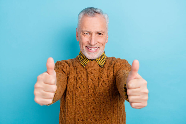 Photo of confident attractive man pensioner dressed brown pullover showing thumbs up isolated blue color background - Foto, Imagen