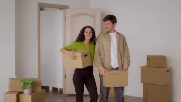 Ευτυχισμένο ζευγάρι κρατώντας χαρτόνι κινείται κουτιά στέκεται στο σπίτι - Πλάνα, βίντεο
