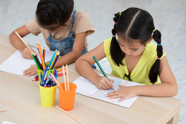 azjatyckie dzieci używają kolorowych ołówków pióro kreatywne rysować obrazy wesoło na stole w klasie z powrotem do koncepcji szkoły - Zdjęcie, obraz