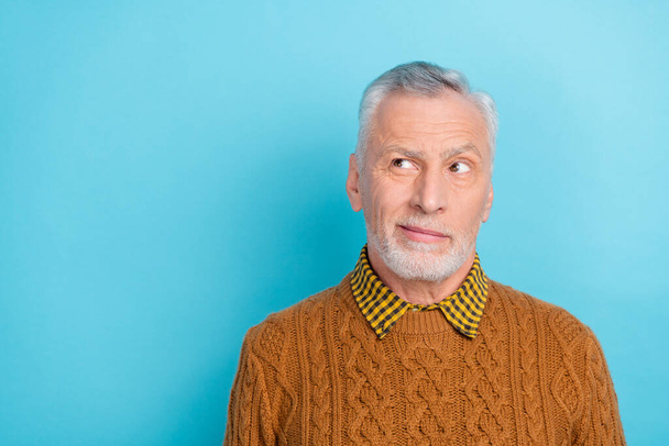 Photo of thoughtful unsure man pensioner dressed brown pullover looking empty space isolated blue color background - Foto, Imagen
