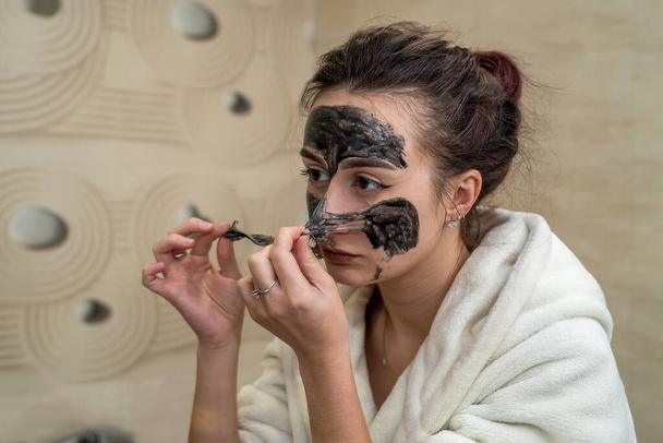 hermosa joven hace una máscara negra para el acné en la cara. concepto de máscara de acné - Foto, imagen