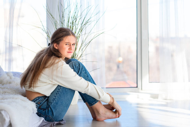 Sad and angry teenage girl sitting on the floor in the room. Teenager problems concept - Foto, Imagen