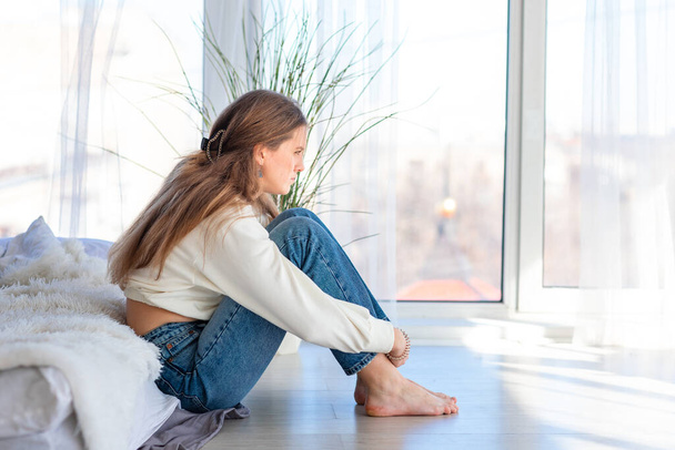 Sad and angry teenage girl sitting on the floor in the room. Teenager problems concept - Foto, Imagen