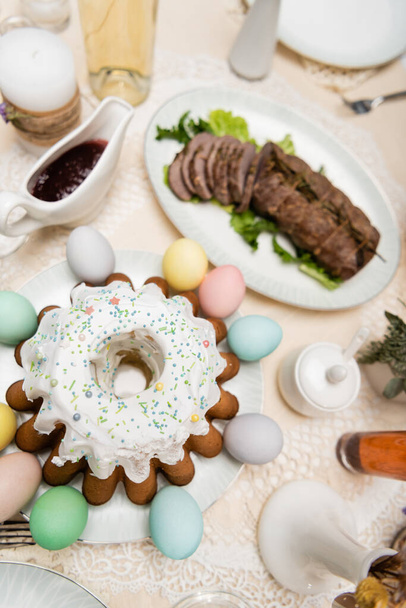 верхний вид вкусный пасхальный торт возле окрашенных яиц на столе подается с пасхальным ужином - Фото, изображение