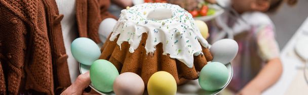 おいしいイースターケーキとクロップドファミリーの近くに描かれた卵バナー - 写真・画像