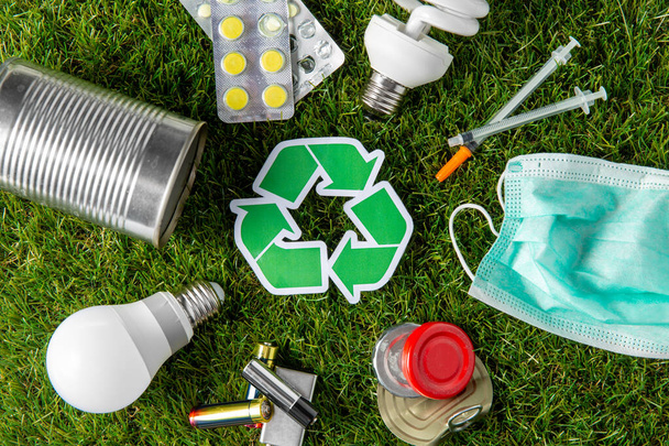 green recycle sign with household waste on grass - 写真・画像