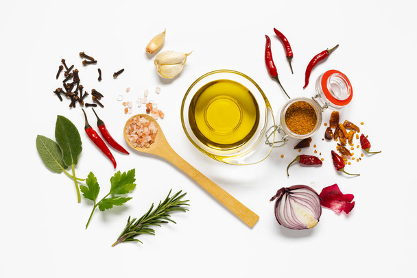 variety of herbs and spices, a bowl with olive oil are arranged on white background. view from above - Photo, image