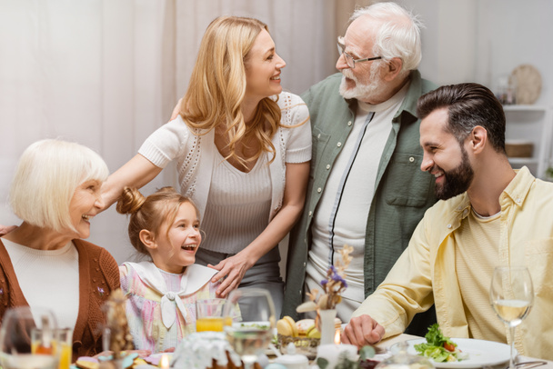 senior man talking to smiling woman during easter celebration with family - Photo, Image