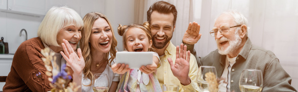 vzrušená rodina mává rukama při videohovoru na smartphonu v blízkosti sklenic na víno, banner - Fotografie, Obrázek