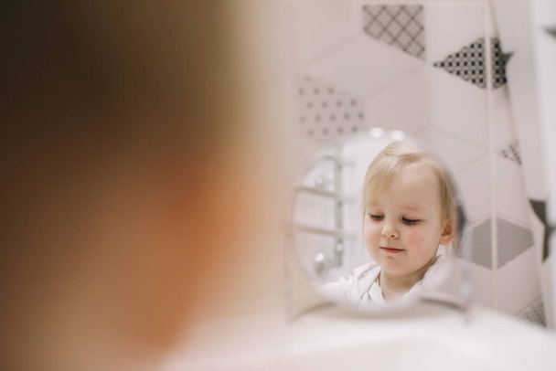 little funny girl brushing teeth and washing hands in the bathroom, reflection in the mirror - Фото, зображення