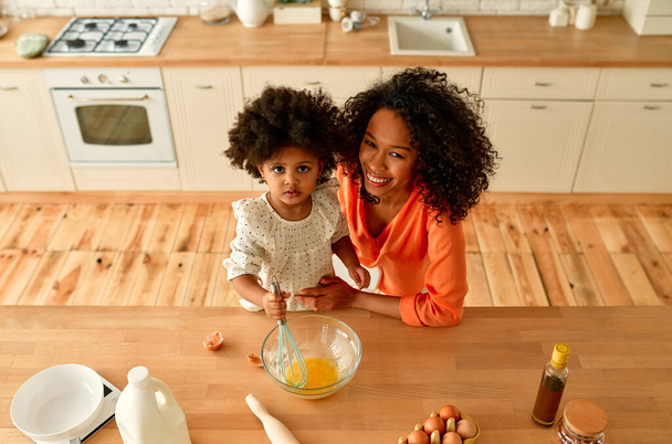Afrikkalainen amerikkalainen nainen hänen pieni tytär kihara pörröinen tukka hauskaa ja tehdä leivonnaisia keittiössä. Äiti ja tytär ruoanlaitto yhdessä. - Valokuva, kuva