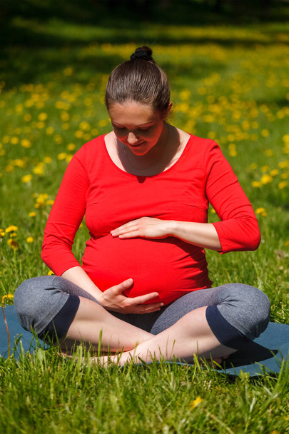 Zwangere vrouw doet asana Sukhasana buiten - Foto, afbeelding