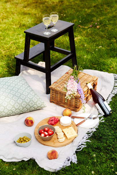 food, drinks and picnic basket on blanket on grass - Foto, Imagem