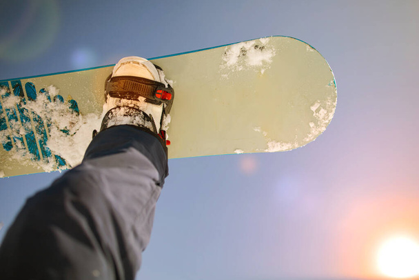 Snowboarder assis au coucher du soleil moment de détente dans la station de ski des Alpes françaises - Concept de sport d'hiver avec l'homme au sommet de la montagne prêt à descendre. jambes sur un snowboard en arrière-plan du ciel. - Photo, image