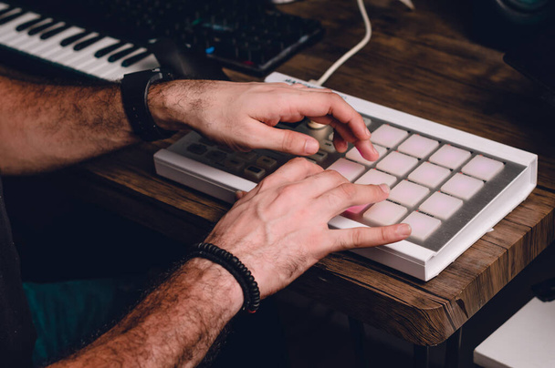 férfi kaukázusi kezét termelő zenét egy midi vezérlő egy asztalon egy otthoni stúdió, zeneipar és termelési koncepció - Fotó, kép