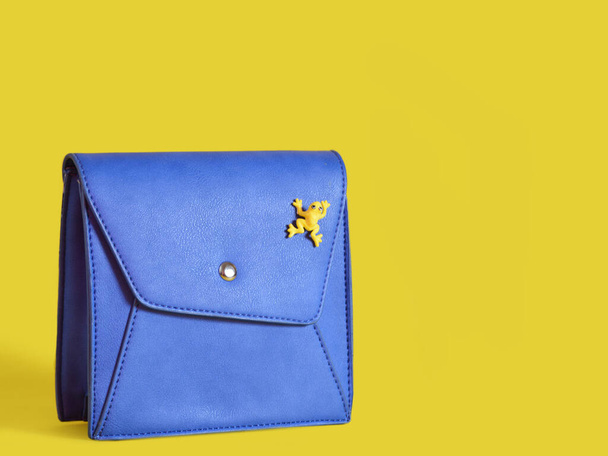 μικρή γυναικεία μπλε τσάντα με ένα βάτραχο σε κίτρινο φόντο - Φωτογραφία, εικόνα