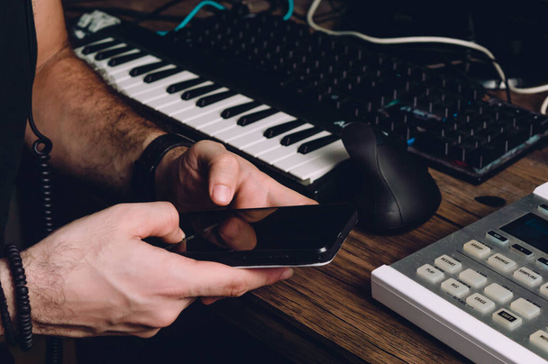 mãos masculinas caucasianas usando um telefone em um estúdio em casa, enviando mensagens, tecnologia e conceito de comunicação. - Foto, Imagem