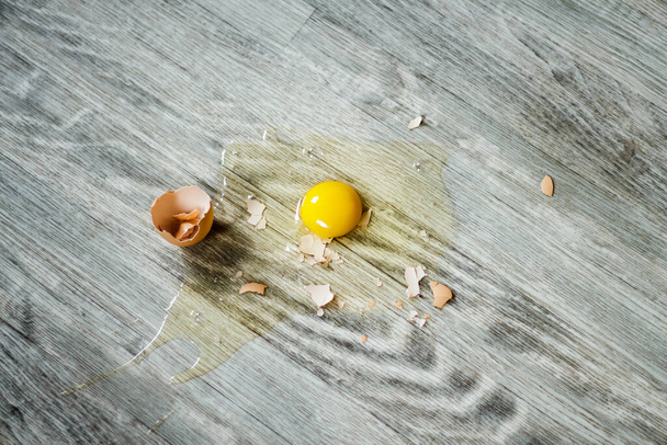 Broken egg on the floor with copy space. Selective focus. This photo can be used for the concept of how to clean up the dropped eggs. - Фото, изображение