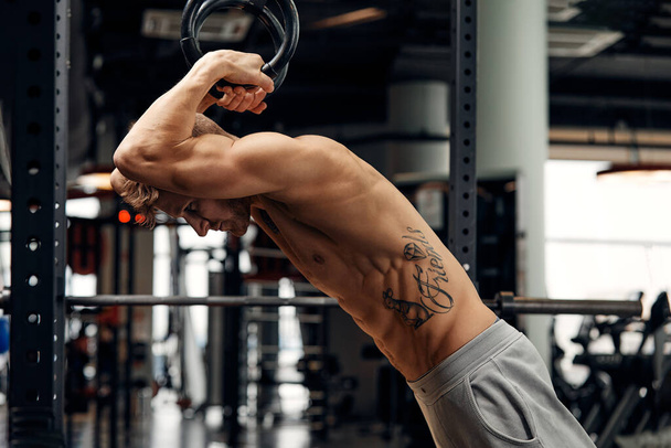Muscle-up exercise young man doing intense cross fit workout at the gym on gymnastic rings. - Foto, imagen