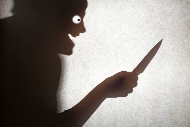 L'ombre d'un maniaque souriant avec un couteau à la main. - Photo, image