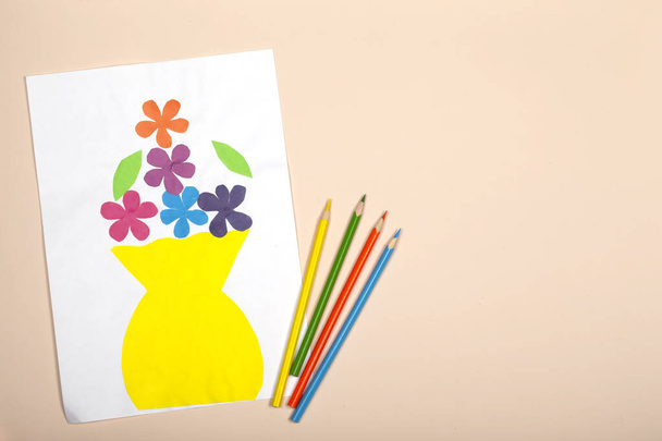 Χειροτεχνία χαρτιού για παιδιά. Εφαρμογή της δημιουργικότητας των παιδιών. Νηπιαγωγείο και σχολή χειροτεχνίας. Σε μπεζ φόντο, ένα βάζο και λουλούδια από χρωματιστό χαρτί. - Φωτογραφία, εικόνα