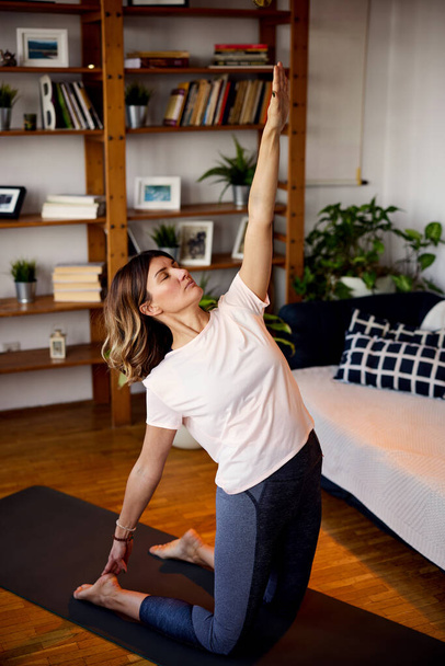 Uma mulher yogi praticando ioga em casa. - Foto, Imagem