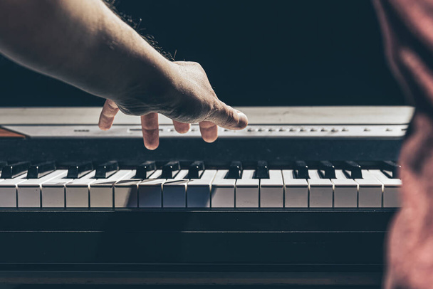 Male hands play the piano keys in the dark. - Valokuva, kuva