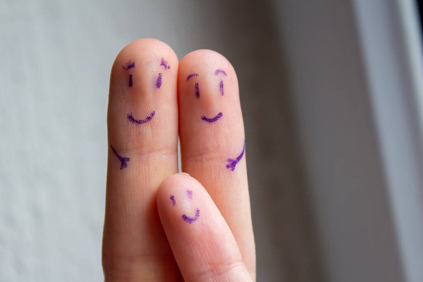 Smiley faces drawn on fingers. Mother, father and child happy family concept. - Foto, immagini