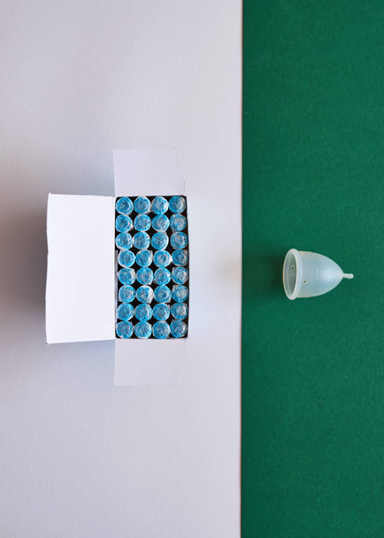 A comparison flat lay of tampons and a more eco-friendly menstrual cup - Zdjęcie, obraz