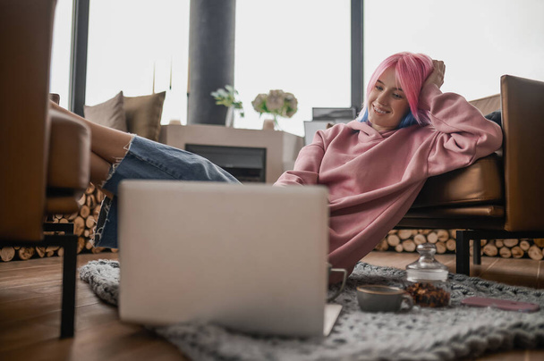 A girl in a pink hoodie feeling relaxed at home - Foto, Bild