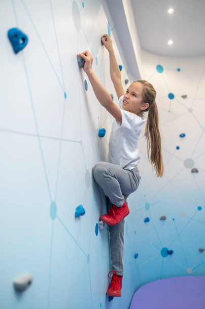 Girl climbing up wall sideways to camera - Fotó, kép