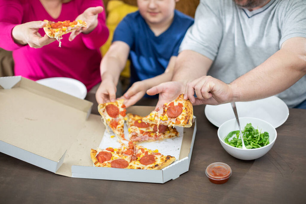 The family divides the pizza slices among themselves. - Foto, Imagem