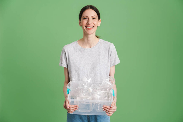 Young happy woman carrying a plastic container full with empty recyclable plastic. Recycling concept - Foto, Imagem
