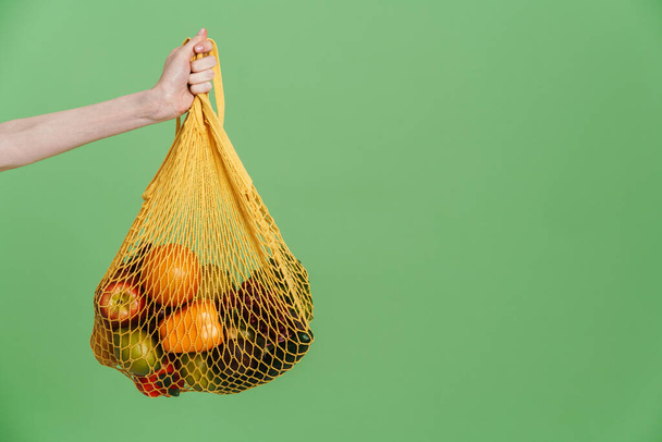 Photo of hand holding textile bag with vegetable isolated over green background - Foto, imagen