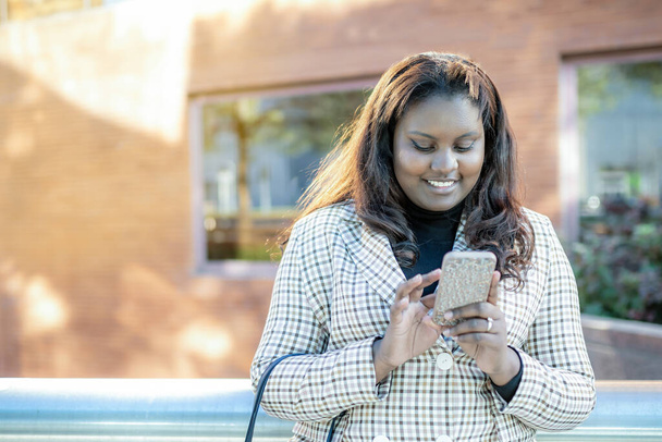 Güzel siyah kız cep telefonuna mesaj yazarken gülümsüyor. - Fotoğraf, Görsel