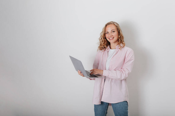 A girl with curly hair on a white background holding a laptop - Photo, Image