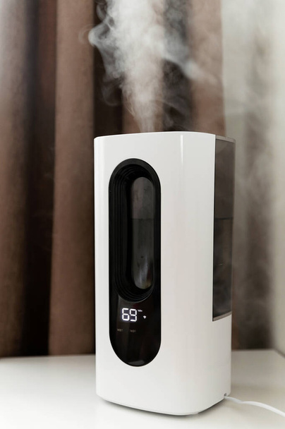 the air humidifier is in the room on the nightstand next to the bed. smart humidifier with wifi and remote control. electronic control panel. - Fotó, kép