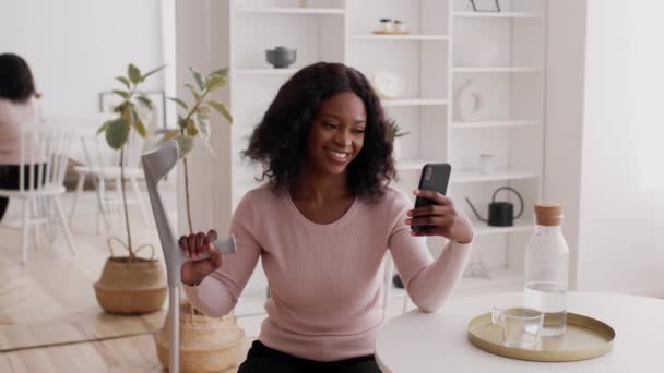 Felice afroamericano femmina making selfie holding stampelle a casa - Filmati, video