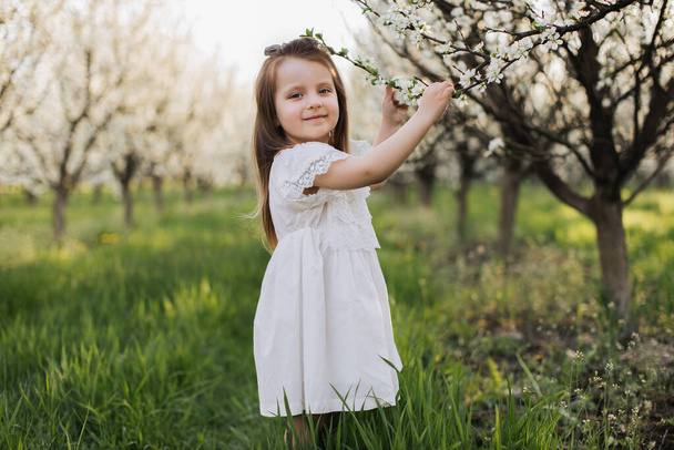 Adorable child posing at garden with blooming apple trees - Photo, Image