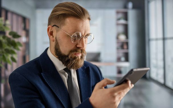 Businessman at office with smartphone - 写真・画像