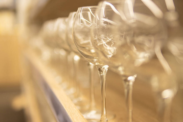 lege glazen bekers voor wijn en andere dranken op een houten plank op een wazige achtergrond - Foto, afbeelding