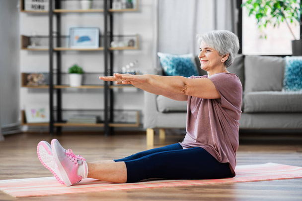 smiling senior woman exercising on mat at home - Valokuva, kuva