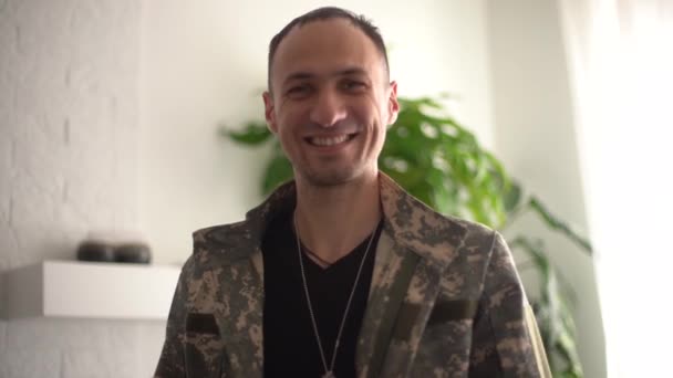 Mozgókép fiatal boldog mosolygós férfi katona álcázott katonai egyenruhában csinál technológia videó hívás a családja vagy barátai csak forduljon haza után küldetés. - Felvétel, videó