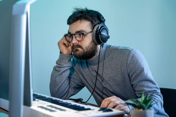 Mannelijke muzikant maakt muziek met behulp van computer en toetsenbord, muzikant werkplek. - Foto, afbeelding