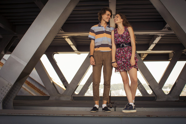 Молода пара обіймає влітку денне світло на мосту конструкції
 - Фото, зображення