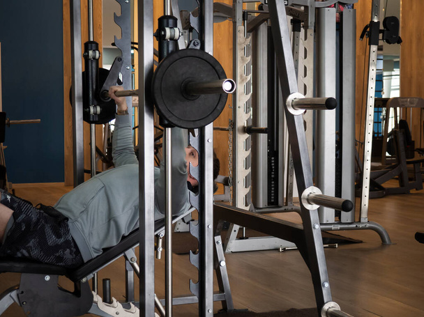 der Typ treibt Sport im Simulator in einem Fitnessclub, der Typ pumpt Muskeln - Foto, Bild