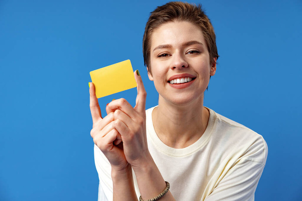 Image of young woman holding business card with copy space on blue background - Foto, Bild